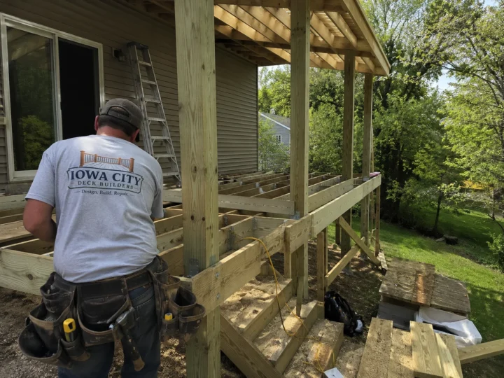 Worker building covered deck framing on a residential deck project in Hills, Iowa.
