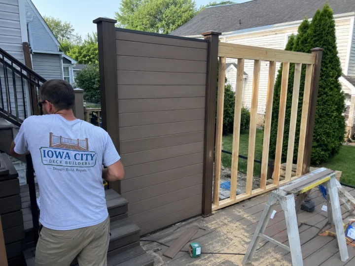 Worker building horizontal privacy screen on a residential deck project in Swisher, Iowa.