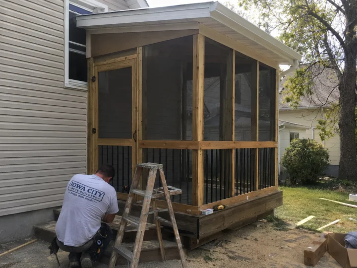Worker building screened porch walls on a residential deck project in North Liberty, Iowa.