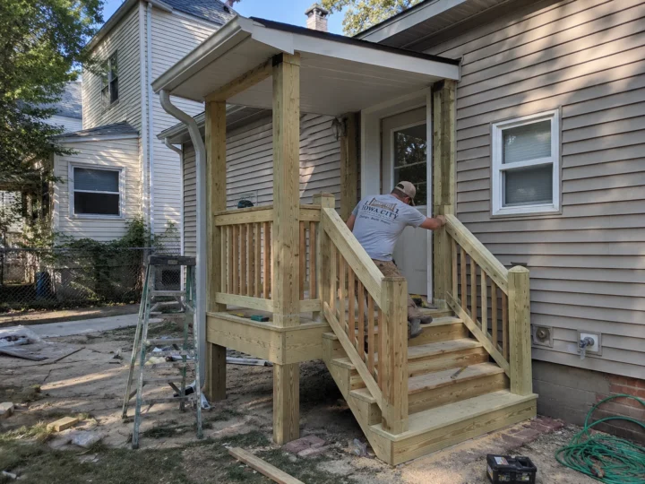 Worker building small covered porch and stairs on a residential deck project in Coralville, Iowa.