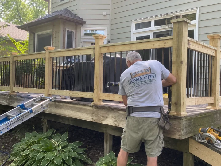 Worker building wood deck railing on a residential deck project in Williamsburg, Iowa.
