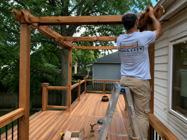 Worker building wood privacy screen and pergola on a residential deck project in Coralville, Iowa.