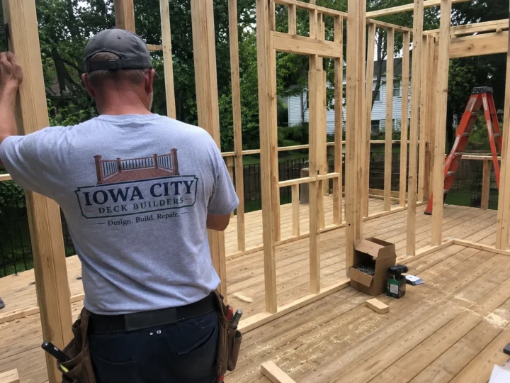 Worker framing screened porch wall on a residential deck project in Iowa City, Iowa.