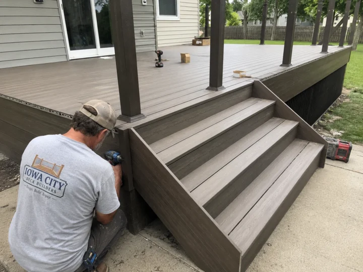 Worker installing composite deck stair treads on a residential deck project in Iowa City, Iowa.