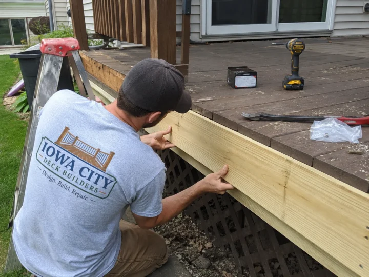 Worker installing deck fascia board on a residential deck project in Coralville, Iowa.