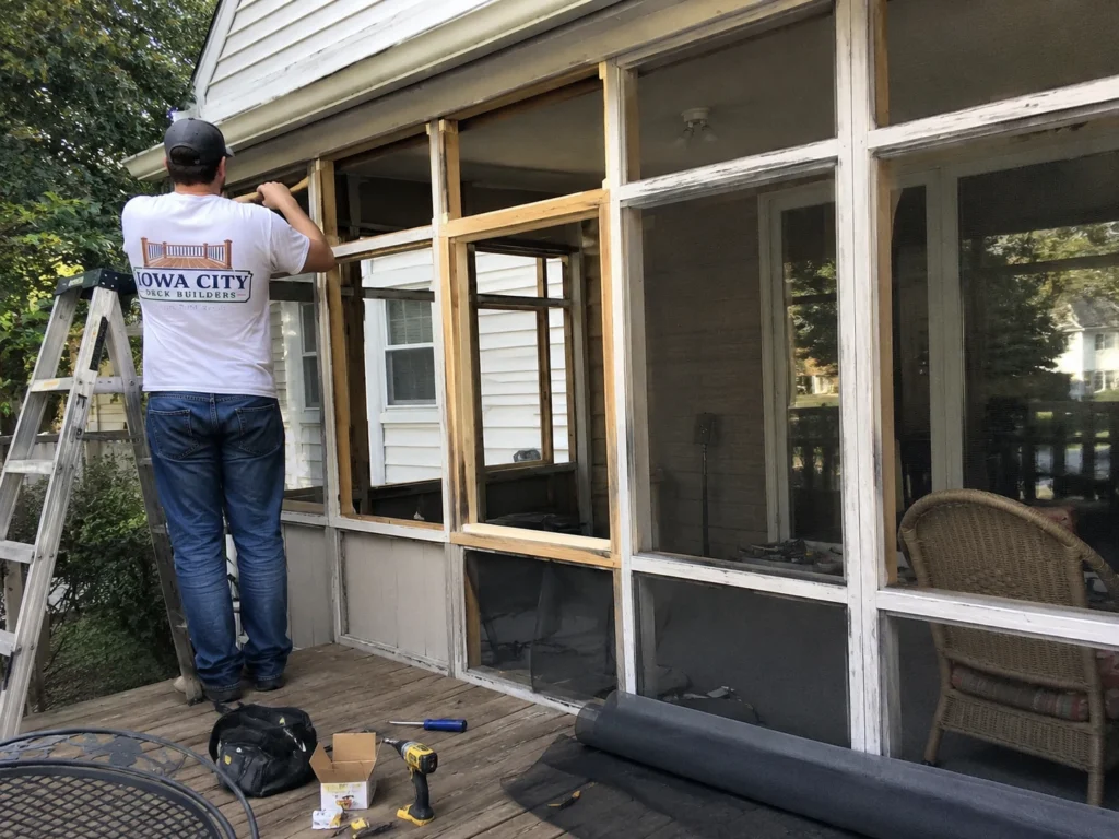 Worker installing screened porch framing on a residential deck project in Iowa City, Iowa.