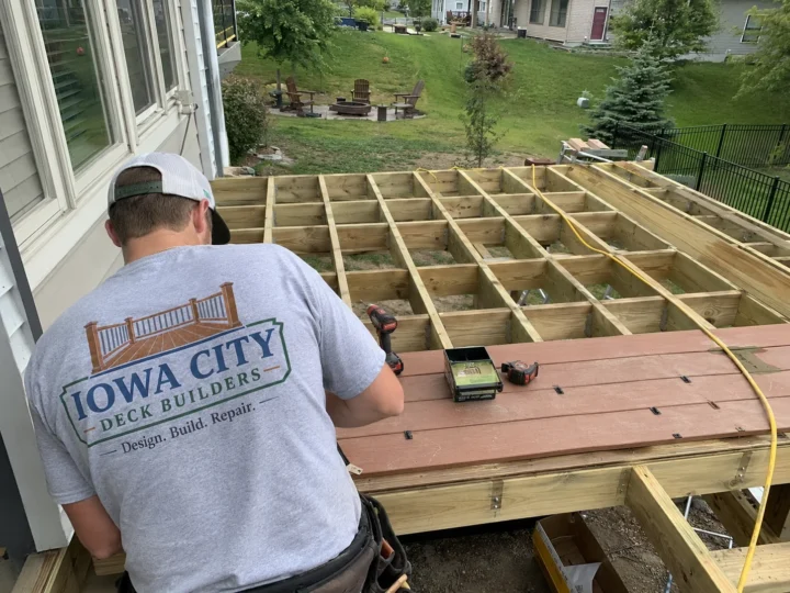 Worker rebuilding deck framing and joists in Amana, Iowa.