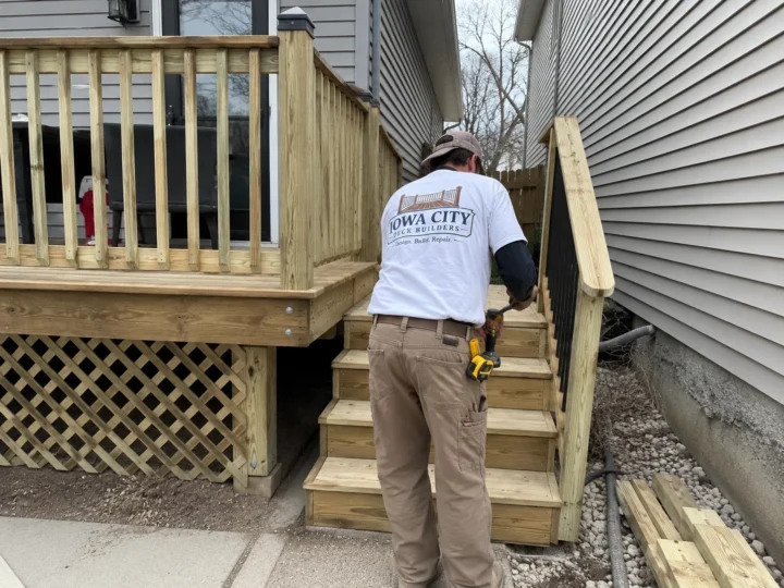 Worker rebuilding wood deck stairs on a residential deck project in Lone Tree, Iowa.