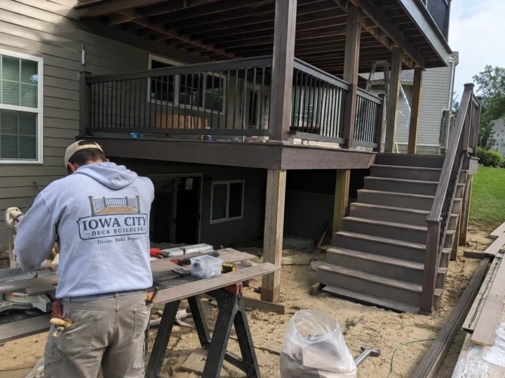 Worker repairing deck stairs and landing on a residential deck project in Amana, Iowa.