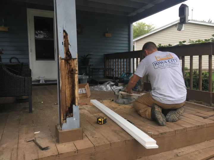 Worker repairing a rotted covered porch post in Williamsburg, Iowa.