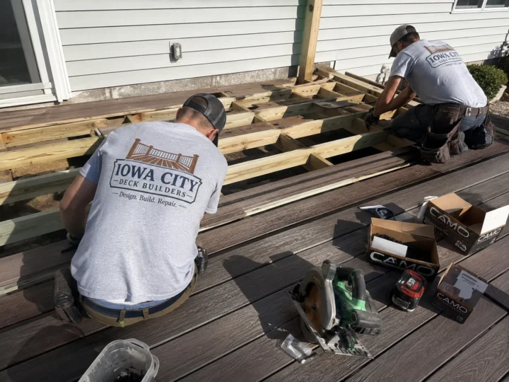 Workers installing composite deck boards on a residential deck project in Solon, Iowa.