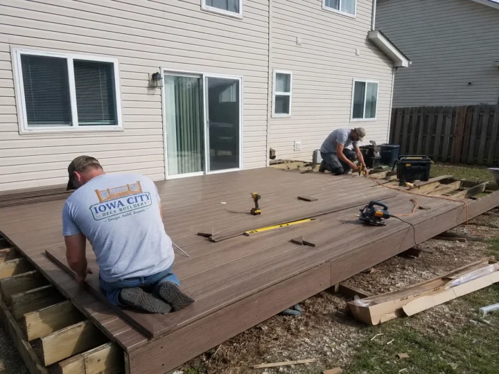 Workers installing composite decking on a residential deck project in Shueyville, Iowa.