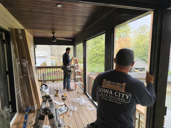 Workers installing screened porch enclosure on a residential deck project in Shueyville, Iowa.