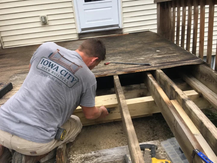 Workers rebuilding weathered deck surface on a residential deck project in Tiffin, Iowa.